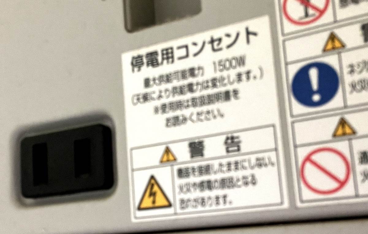 パワーコンディショナー側面の停電用コンセント。ラベルに「最大供給可能電力 1500W」「天候により供給電力は変化します」と記載されている